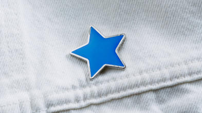 Blue enamel star-shaped pin on denim pocket