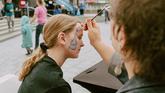 Child getting face paint from a volunteer at the walk for wishes event