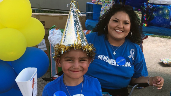 Khonner with a cowbell and party had smiling with his mom.