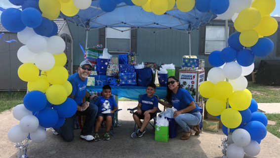 Wish Kid Khonner and brother Koda with Make-A-Wish Volunteers under a balloon arch.