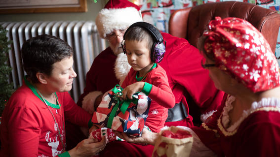 4-year-old Michael sits in Santa's lap and looks at a toy tractor with his mother