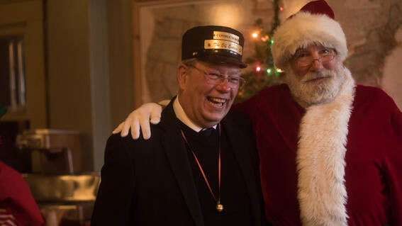 Train conductor stands with Santa and smiles