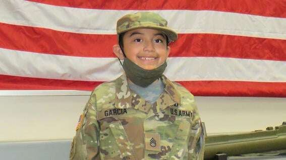 Miguel grins in front of a US flag