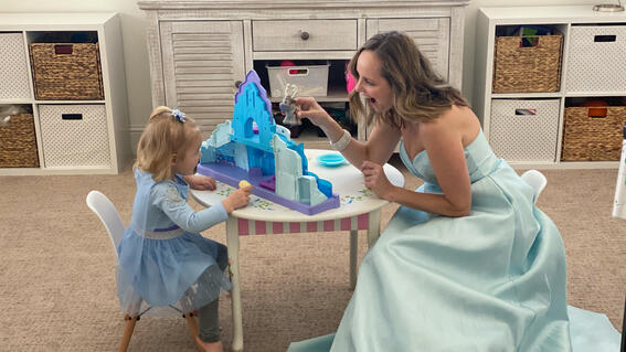 Volunteer Nicole and her niece Presley playing with a castle at a kids table while dressed up for wishes