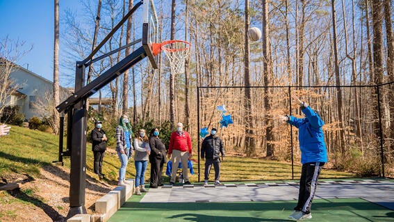 Luke shooting a basketball with family and friends watching