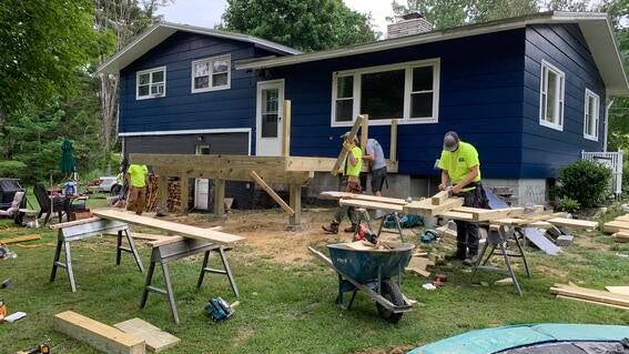 A blue house has construction materials around it.