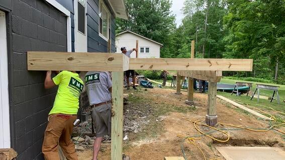 Close-up of men working on a deck addition to blue house