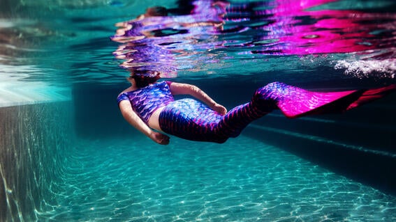 Emma in a mermaid tail swimming underwater