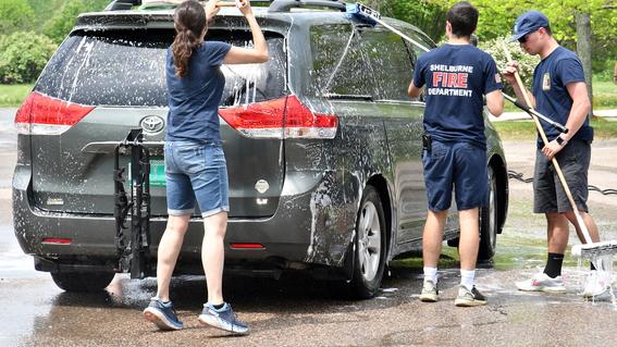 a car is surrounded by first responders washing with long brushes