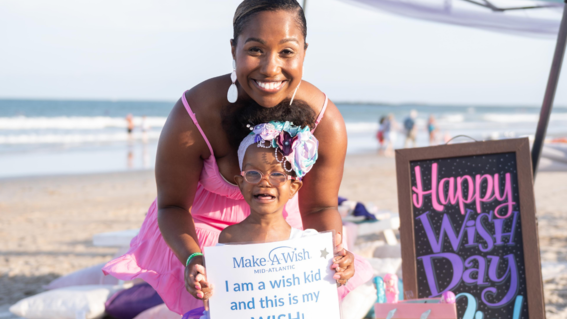 Nia and mom on beach with wish kid sign