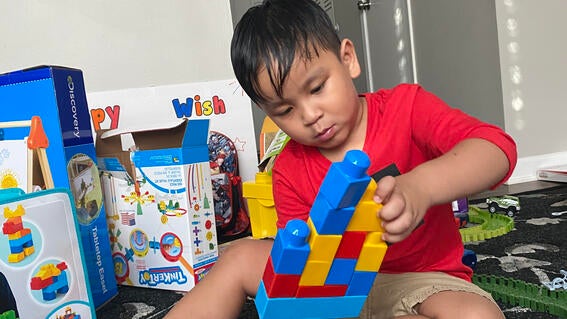 Boy in red shirt holds large building blocks.