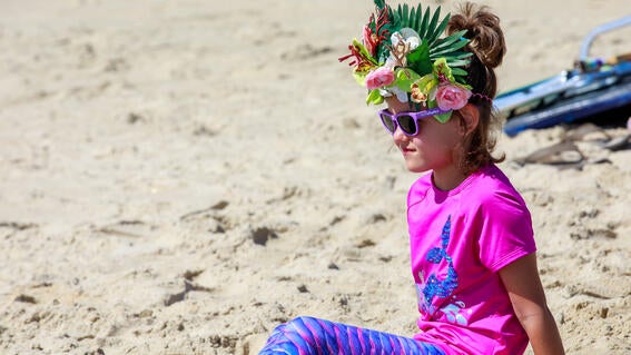 Maggie on beach wearing her crown and tail.