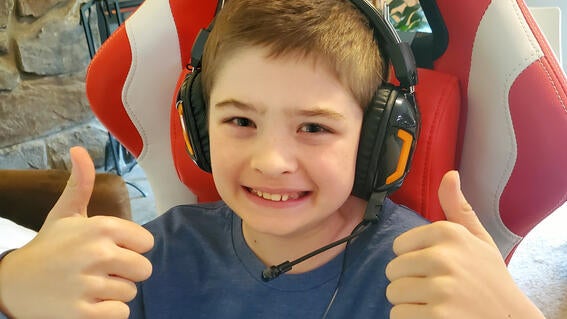 Boy wearing headphones gives two thumbs up.