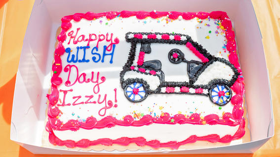 Izzy's wish cake with pink icing and a golf cart drawing