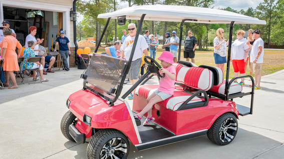 Wish kid Izzy trying to reach the pedals in her new pink golf cart