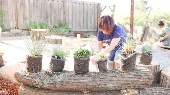 A volunteer helps with plants for Yahya's backyard makeover