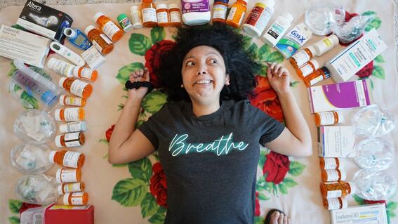 Nicole laying on the ground with assorted medications around her head