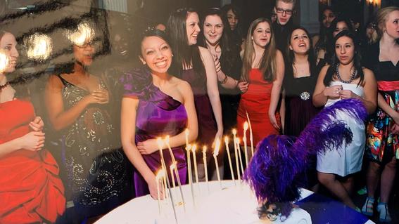 Nicole in a purple dress surrounded by her friends with a cake and candles