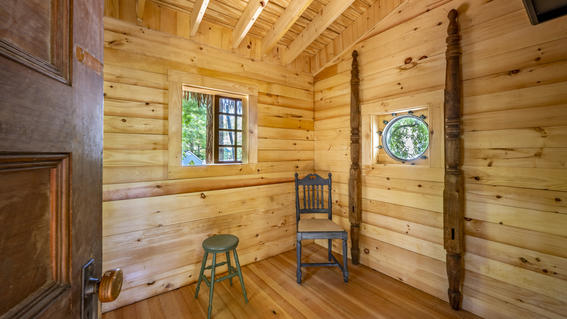 The interior of Libby's treehouse, which is a warm wood tone with windows and a high ceiling