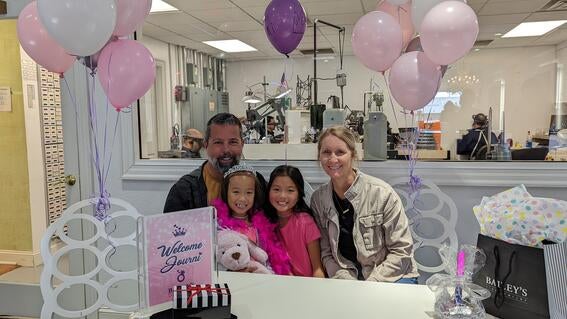 Journi and her family seated behind a table with balloons and gifts