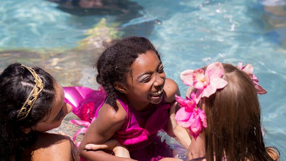 Tatiana smiles with mermaids in the water on her wish