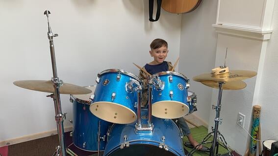 Uriah plays his drum set in his Music House