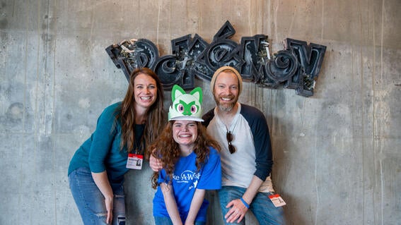 Selah in front of Pokemon sign with parents