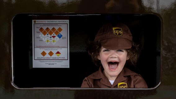 JoJo with a big grin on his face as he sits inside his mini UPS delivery truck