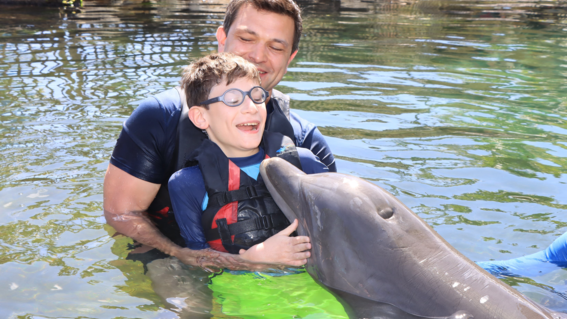 Nikita and his dad swimming with a dolphin