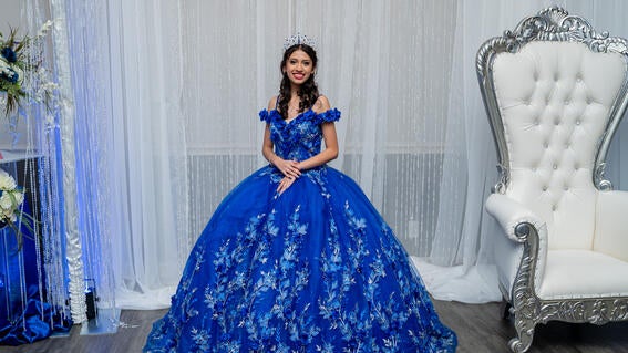 Wish kid Alexis standing in her blue quinceañera dress smiling