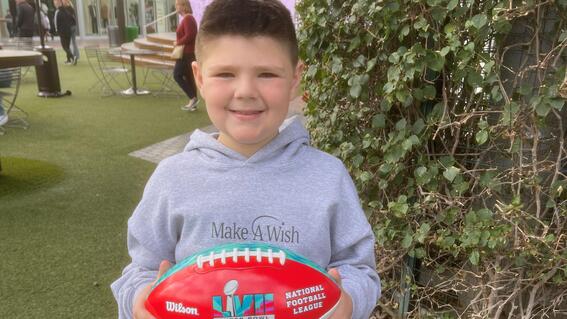 wish kid holding Super Bowl football at Dave & Buster's party