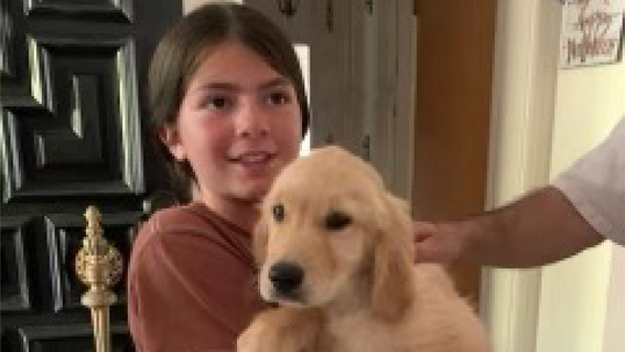 Bianca holds her new puppy, smiling