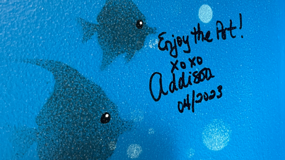 Photo of Addison's signature on a wall mural, saying "Enjoy the Art!"