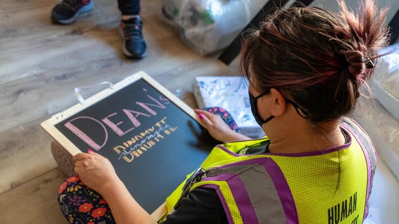 An Amazon volunteer writes on Dean's chalk sign