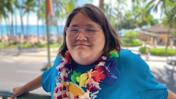 Rusha smiles in a lei with the beach in the background
