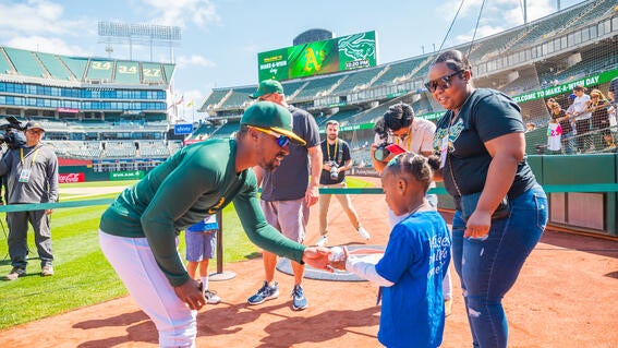 Athletics' left fielder Tony Kemp giving wish kid Akira a signed baseball.