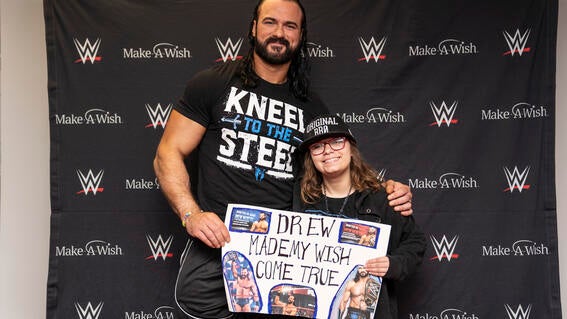 Giovanna holding her hand made sign with Drew McIntyre 