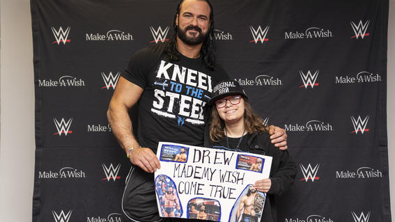 Giovanna holding her hand made sign with Drew McIntyre 