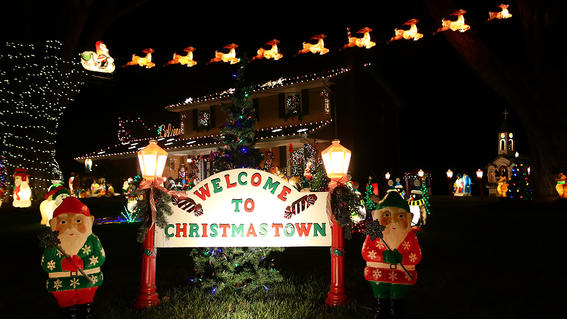 A bright sign that reads welcome to Christmas town, with two elves on the sides. 