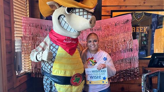 Laxy, 18, poses with the Texas Roadhouse armadillo while enjoying lunch after her shopping spree wish.