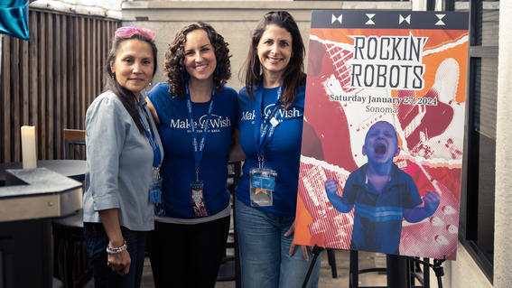 Nolan's wish planner, Becki Smith, and wish granters Denise Pepp and Maria Tribble in front of Nolan's custom Rockin' Robots on his wish day celebration.