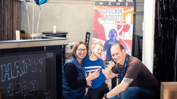 Nolan, his mom Jennifer, and his dad Tito posing in front of his custom Rockin' Robots on Nolan's wish day celebration.