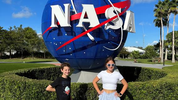 Ezra and his sister standing in front of the NASA sign