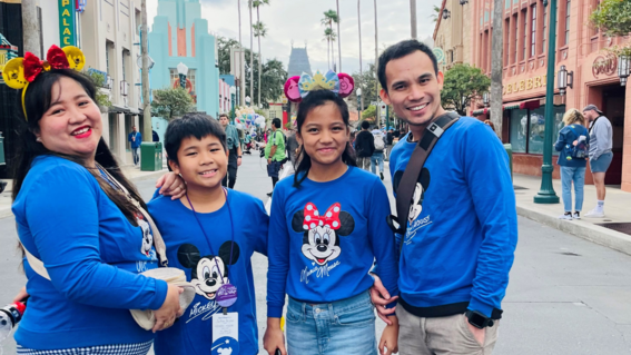 Jeshua and his family stand in disney world street in blue shirts.