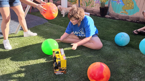 Every day, Lily spends time playing in the grass and with her colorful toys.
