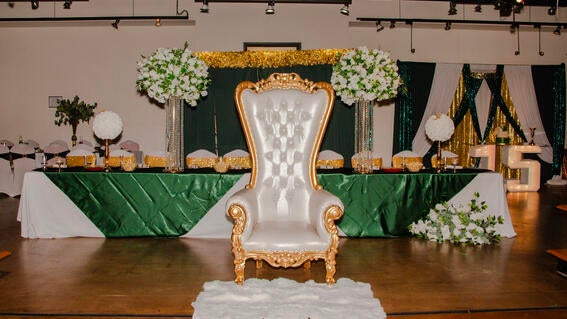 An elegant ballroom showing a large white and gold thrown with decorations behind