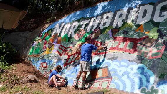 Nate and Ben take a break to sit in front of Ben's colorful mural on a rock face in Northbridge