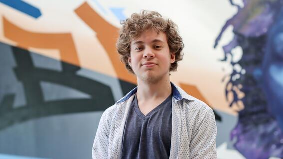 Nate poses in front of a mural at MassArt
