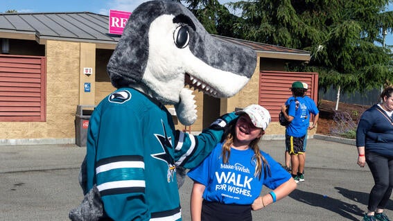 Sharkie playfully bites the head of a Walk guest