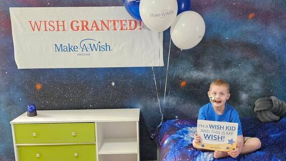 Aleksander enjoys his new galaxy-themed room and holds a "This is my wish" sign.